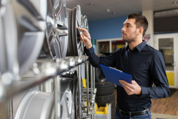 auto business owner and wheel rims at car service Mechanic inspecting wheels