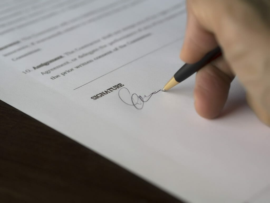 A hand signing a piece of paper 