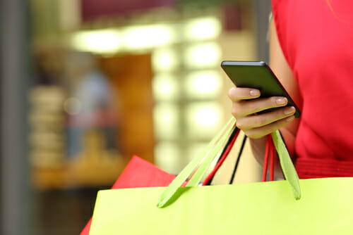 A woman carrying a shopping bag and a cell phone 